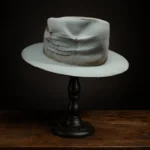 Back view of beige Memento custom fedora hat showing hand-stitched quote patch and distressed felt texture