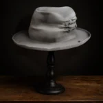 Left side view of gray Memento fedora hat showing stitched quote patch and soft felt texture
