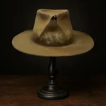 Front view of the Rooster Cogburn Replica Hat, a handcrafted brown distressed felt fedora inspired by Jeff Bridges in True Grit (2010), displayed on a wooden stand.