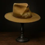 Side view of the handcrafted brown distressed Rooster Cogburn Replica Hat inspired by Jeff Bridges in True Grit (2010), displayed on a wooden stand.