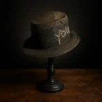 Left side view of the ScrewU handmade felt hat showing stitched “YOU” and metal screw