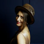 Woman wearing the ScrewU handmade felt hat in dark brown with stitched “YOU” and metal screw detail