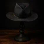 Front view of the handcrafted distressed black felt replica hat inspired by Devil Anse Hatfield from the Hatfields & McCoys series, displayed on a wooden stand.