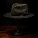 Angled side view of the handcrafted distressed black felt replica hat inspired by Devil Anse Hatfield from the Hatfields & McCoys series, displayed on a wooden stand.