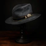 Side view of the handcrafted distressed black felt replica hat inspired by Devil Anse Hatfield from the Hatfields & McCoys series, displayed on a wooden stand.
