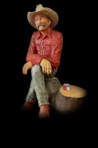 Jack Montclair figurine sitting on a log, wearing a red shirt and cowboy hat, storytelling mascot for Jack’s Custom Hats